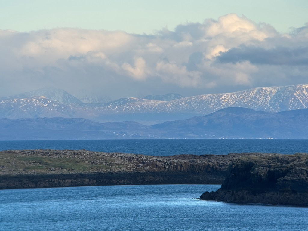 with snowy mountains on scottish mainland as background, the minch's open ocean is separated by two small islands