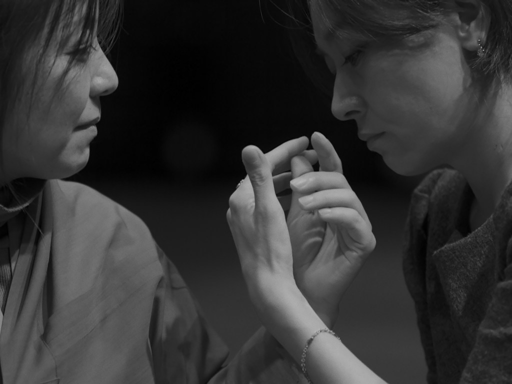 two asian women looking at how their hands are entangled