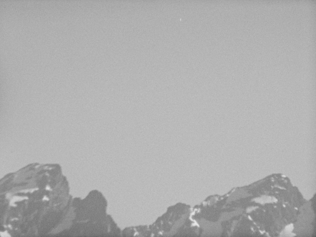 slanted mountain tops covered in snow spots against blue sky