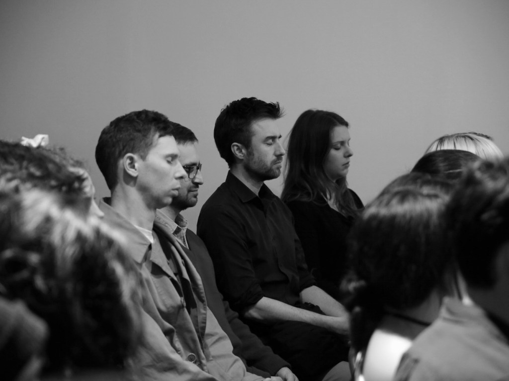 a group of people with their eyes closed sitting in a space