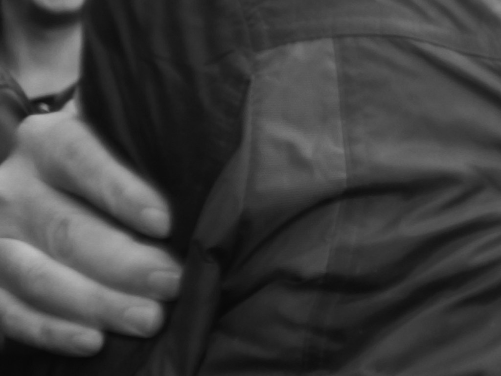 a hand pulling the arm dressed in a jacket with stripes